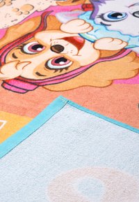 Tappeto morbido e colorato con disegni di cani dei cartoni animati e accenti rosa, beige e blu. I bordi hanno un bordo azzurro chiaro.