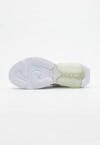 Semelle d'une chaussure de sport blanche et translucide avec des motifs de grip texturés et une section de talon rembourrée, présentée sur un fond uni.