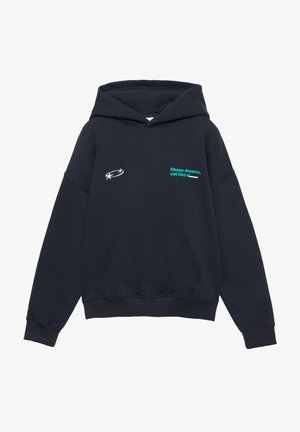 Marineblauwe hoodie met capuchon, voorzien van een zak aan de voorkant, een zilver sterlogo en groene tekst op de borst met de boodschap "Volg je dromen, niet de likes!"