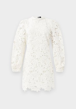 Hvidt blondedress med blomster mønstre, lange pufærmer, en høj halsudskæring og en bølget kant for ekstra detalje.