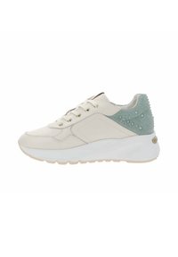Baskets beiges avec une semelle blanche épaisse, des lacets couleur crème et un talon vert texturé orné de détails circulaires en relief.