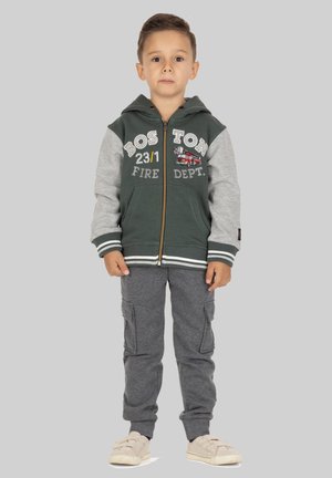 Reißverschluss-Hoodie mit grünem Körper und grauen Ärmeln, ausgestattet mit dem Text "BOSTON FIRE DEPT" und einer Feuerwehrwagen-Grafik. Kombiniert mit grauen Cargo-Hosen.