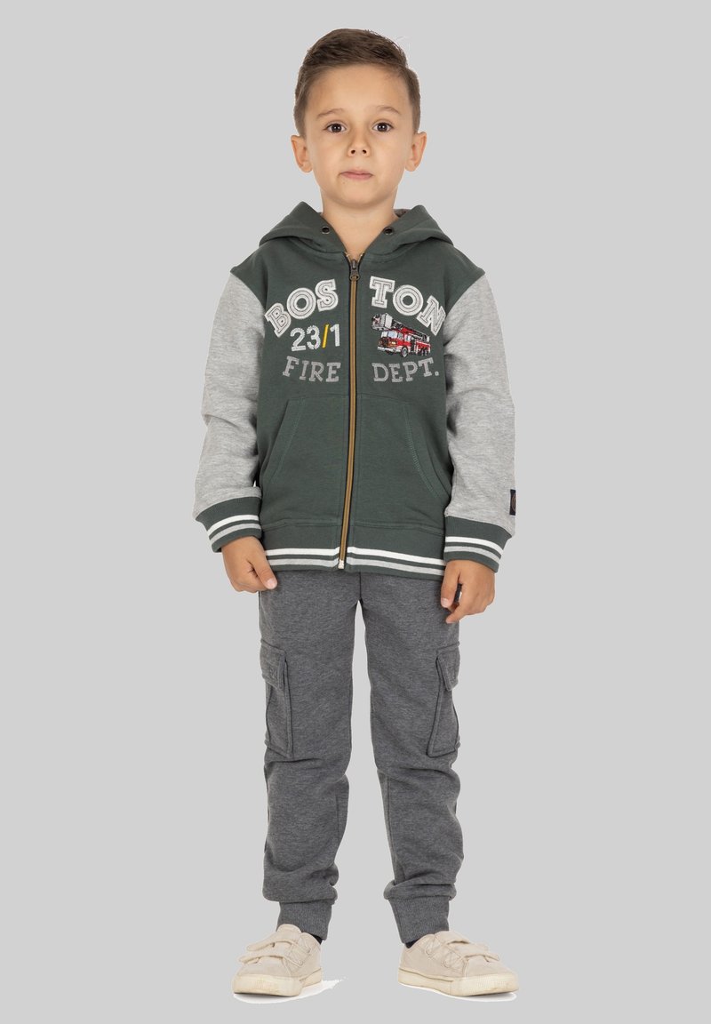 Ritssluiting hoodie met groene romp en grijze mouwen, met de tekst "BOSTON FIRE DEPT" en een afbeelding van een brandweerauto. Gecombineerd met grijze cargobroek.