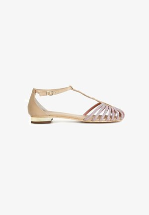 Beige sandal med flad hæl, der har et åbent tådesign, vegansk lædermateriale og indviklet perleudsmykning på forsiden.