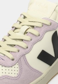 Αθλητικό παπούτσι VEJA με ελαφρύ μοβ σουέντ και μπεζ συνθετικό δέρμα. Κρεμ κορδόνια και μαύρο λογότυπο στο πλάι. Παρουσιάζει διάτρητες λεπτομέρειες.