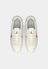 Balti tinkliniai batai su tekstūruota paviršiumi ir raudonu Nike swoosh. Savybės: plokštys raišteliai ir paminkštintas apykaklė, sukurti patogumui.