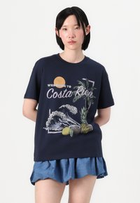 Navy cotton t-shirt with a vibrant graphic featuring waves, palm trees, and tropical fruits, complemented by a round neckline and short sleeves.
