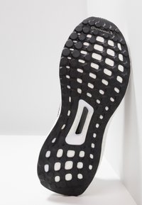 Černobílá gumová podrážka sportovní obuvi s kruhovými gripy a značkou Continental blízko špičky.