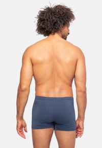 Boxer aderenti blu navy in un tessuto texturizzato con un piccolo motivo geometrico, dotati di una vita a media altezza e un taglio corto.