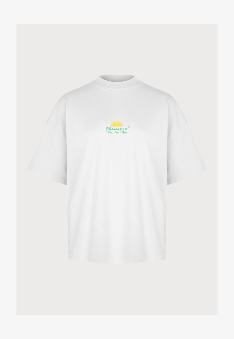 T-shirt en coton blanc avec un col rond et des manches courtes. Présente un logo "PEGADOR" en broderie verte et jaune avec un motif de soleil.