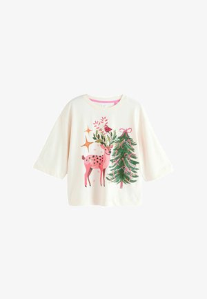 Cremefarvet oversized t-shirt med en pink hjort, et grønt juletræ og festlige detaljer som bånd og stjerner i livlige farver.