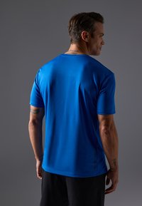 Meeste sinine lühikeste varrukatega sportlik särk, mis on valmistatud siledast ja kergest materjalist. Omab ümarat kaelaauku ja delikaatseid külgkaunistusi ventilatsiooni jaoks.