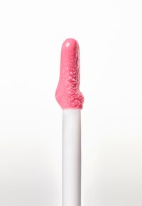 Punta de silicona rosa con cerdas texturizadas, unida a un mango blanco. La punta tiene una forma redondeada y una pequeña hendidura.