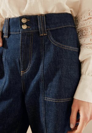 Jeans med hög midja, utrustade med två metallknappar, kontrasterande orange sömmar och framfickor. Mörkblå färg.