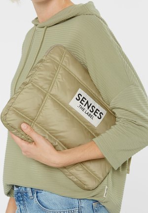 Quilted laptop sleeve in muted olive green, made from smooth nylon. Features a prominent black and white logo patch and subtle stitching.