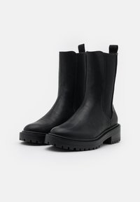 Czarne botki za kostkę wykonane z gładkiej skóry, z elastycznymi bocznymi panelami, zaokrąglonymi noskami i teksturowanymi gumowymi podeszwami dla lepszej przyczepności.