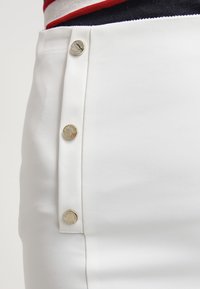 Valkoinen verhoilukangas, jossa on sileä pinta ja metallinäppäimet sivuilla, luoden siistin ja käytännöllisen muotoilun.