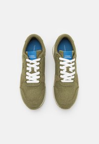 Pár olivově zelených tenisek Tommy Hilfiger s bílými šňůrkami a modrými stélkami, zobrazených shora na bílém pozadí.