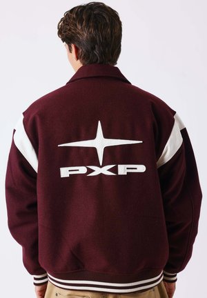 Personne portant une veste universitaire bordeaux et blanche avec une étoile et le logo "PXP" dans le dos, tournée dos à la caméra.