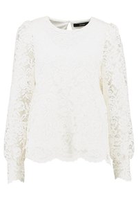 Blusa bianca in pizzo con maniche lunghe e puffate. Presenta un collo rotondo e una chiusura a chiave sul retro. Motivo floreale delicato in tutto il capo.