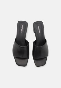 Black leather slide sandals with a wide front band, open heel, square toe shape, and minimalistic design featuring a low block heel.
