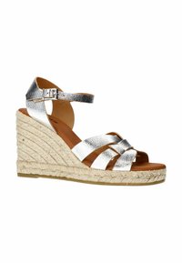 Zilveren metalen espadrille wedge sandaal met vier kruisbanden, verstelbare enkelband en een jute-wikkelde platformzool. Bruine binnenvoering.
