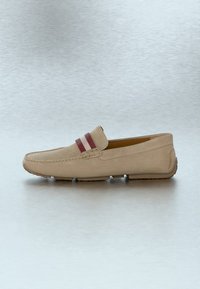 Mocassin en daim beige avec une bande rayée bordeaux et blanche sur le dessus et une semelle en caoutchouc avec des rainures visibles.