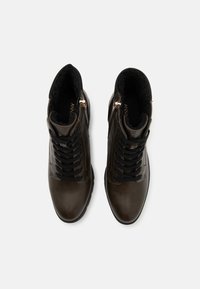 Brown leather ankle boots with black laces, textured insoles, and gold zipper accents, featuring a high-top design for support.