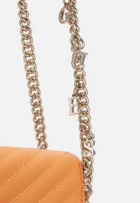 Pomarańczowa torebka pikowana z łańcuchem w srebrnym kolorze, z zawieszkami w postaci metalowych liter. Gładka faktura i usztywniony prostokątny kształt.