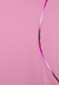 Haut rose ajusté avec une texture lisse, présentant une découpe incurvée avec une transition en dégradé du rose clair au rose foncé le long du bord.