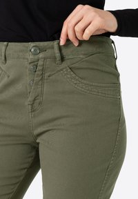 Groene katoenen blend broek met een hoge taille, voorzien van een knoopsluiting, gebogen voorkwatsen en een soepele textuur.