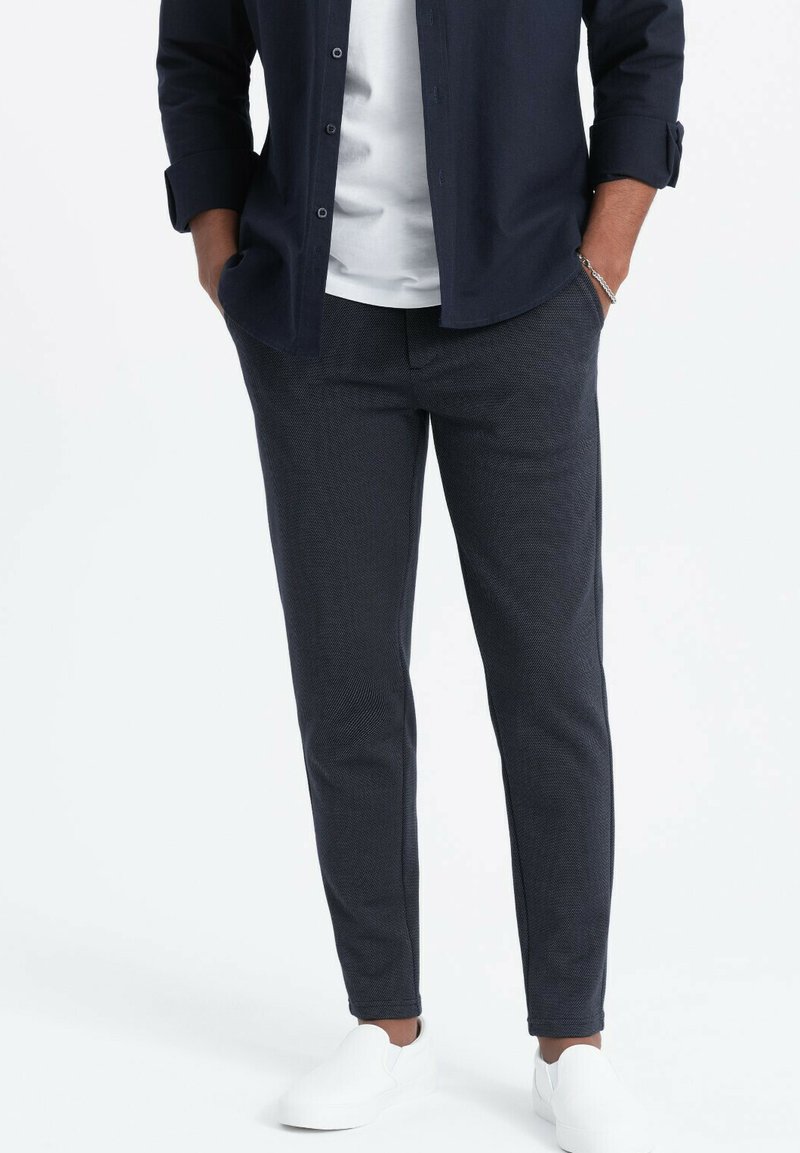 Pantaloni navy a trama con vestibilità slim, dotati di tasche laterali. Abbinate a una maglietta bianca e scarpe slip-on bianche.