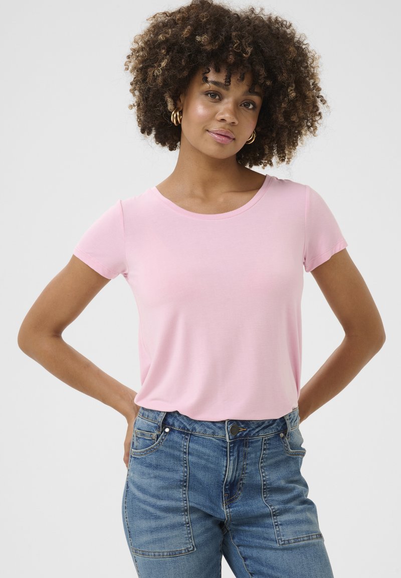 Camiseta corta de manga corta de color rosa claro con cuello redondo, hecha de una tela suave, combinada con unos vaqueros de tiro alto azules que cuentan con bolsillos funcionales.