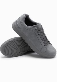 Zapatillas de ante gris con suelas de goma, que cuentan con punta redondeada, cierre de cordones y un acabado texturizado en la suela.