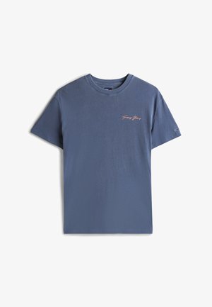 Camiseta de algodón azul con cuello redondo, mangas cortas y un logo bordado en rosa de "Tommy Jeans" en el pecho. Textura suave, corte casual.