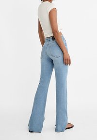 Lichtblauwe flared jeans met een hoge taille, achterzakken en minimale slijtage. Gemaakt van denim, met een gladde afwerking.