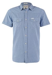 Chemise bleue à carreaux à manches courtes avec deux poches poitrine et boutons-pression blancs, étiquette de la marque Wrangler sur la poche et le col.