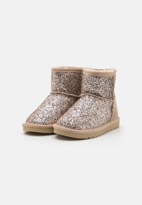 Třpytivé ankle boots v růžovém zlatě s měkkou podšívkou, materiálem podobným semiši a texturovanou gumovou podrážkou. Vyznačují se jednoduchým, klasickým tvarem.