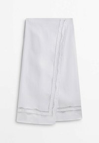 Biały bawełniany obrus z teksturowaną bordiurą i misternym koronkowym wzorem wzdłuż dwóch brzegów, tworzący wyrafinowane wykończenie.