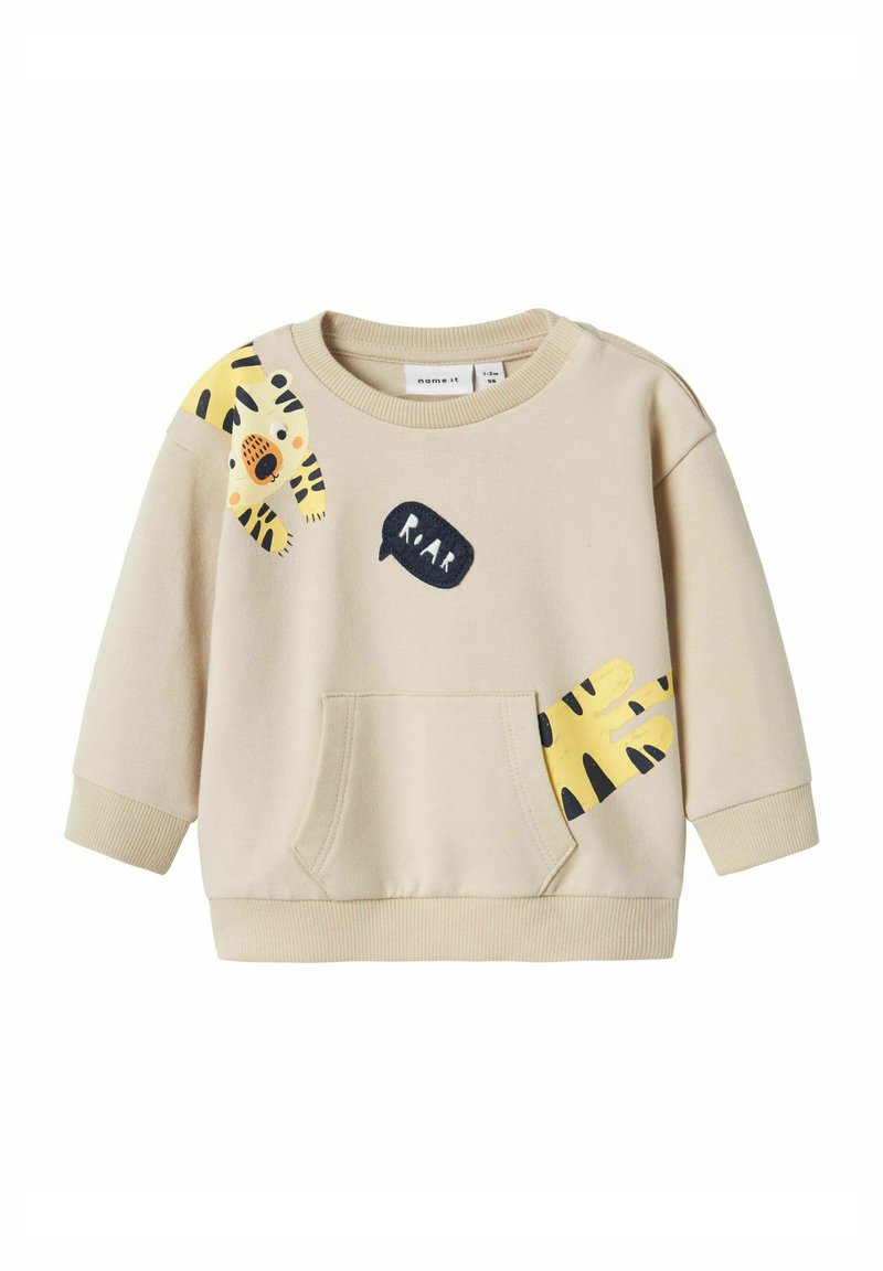Beige huppari pitkillä hihoilla, etutaskulla ja leikkisillä keltaisilla ja mustilla tiikeriprintillä. Sisältää mustan "RAAR" puhekuplan yksityiskohdan.