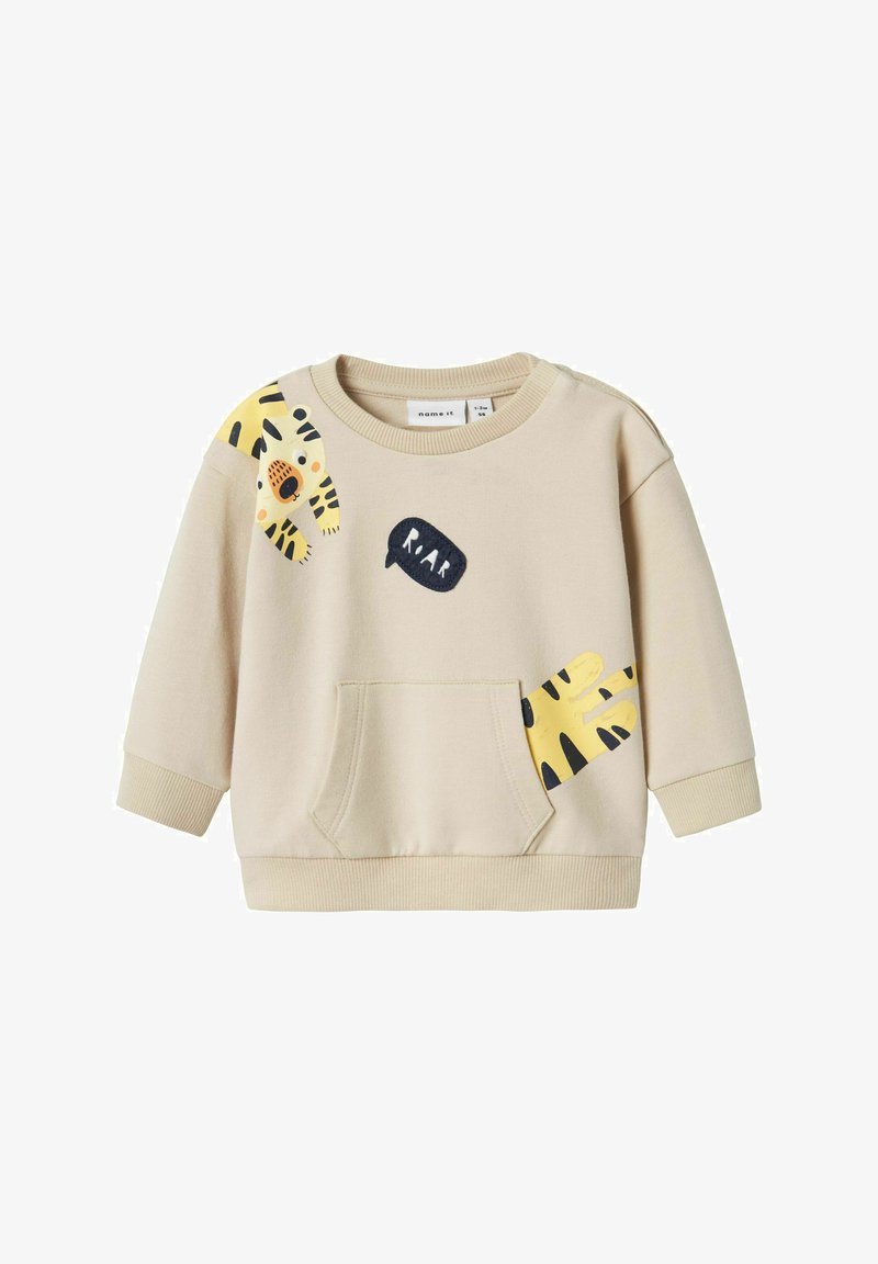 Beige sweatshirt met lange mouwen, een voorkantzak en speelse gele en zwarte tijgerprints. Heeft een zwart "RAAR" spraakwolkdetail.