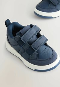 Granatowe sneakersy z rzepami, wykonane z skóry i siateczki, z białą gumową podeszwą, perforowanym czubkiem oraz pętelką z tyłu.