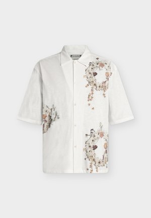 Chemise blanche à manches courtes boutonnée, avec des motifs pâles de couronnes florales sur la poitrine et près de la taille, dotée d'un col classique.