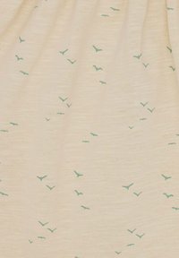 Lichtbeige stof met een zachte textuur, met verspreide turquoise vogel silhouetten in verschillende maten over het oppervlak.