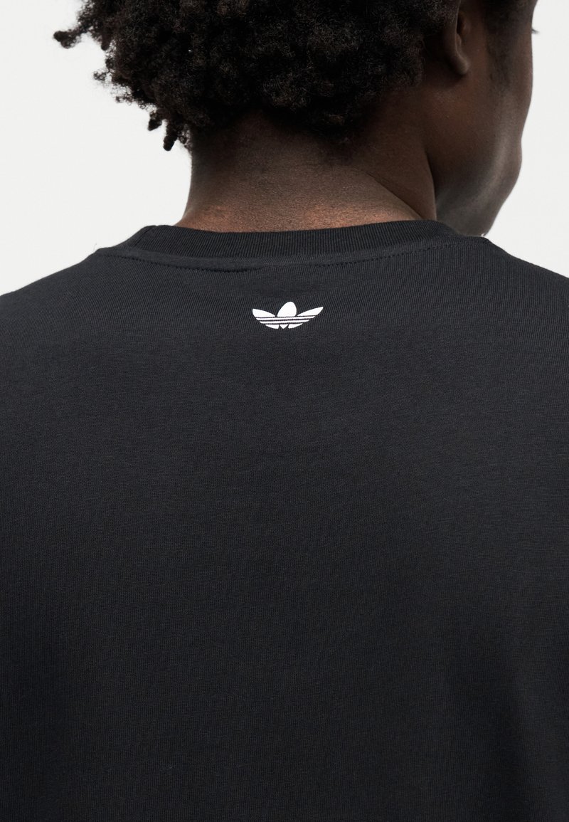 Czarny bawełniany T-shirt z okrągłym dekoltem i małym białym logo na plecach. Gładka tekstura i prosty design, dopasowany krój.