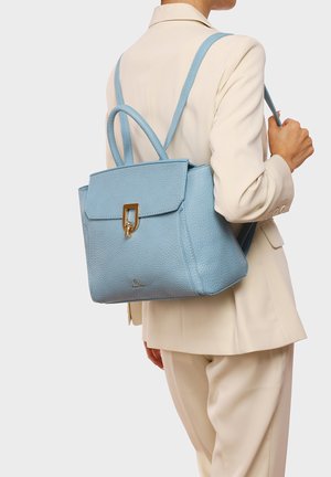 Zaino in pelle testurizzata blu chiaro con una forma strutturata, un pattino frontale e una chiusura in metallo dorato, indossato sulla schiena.