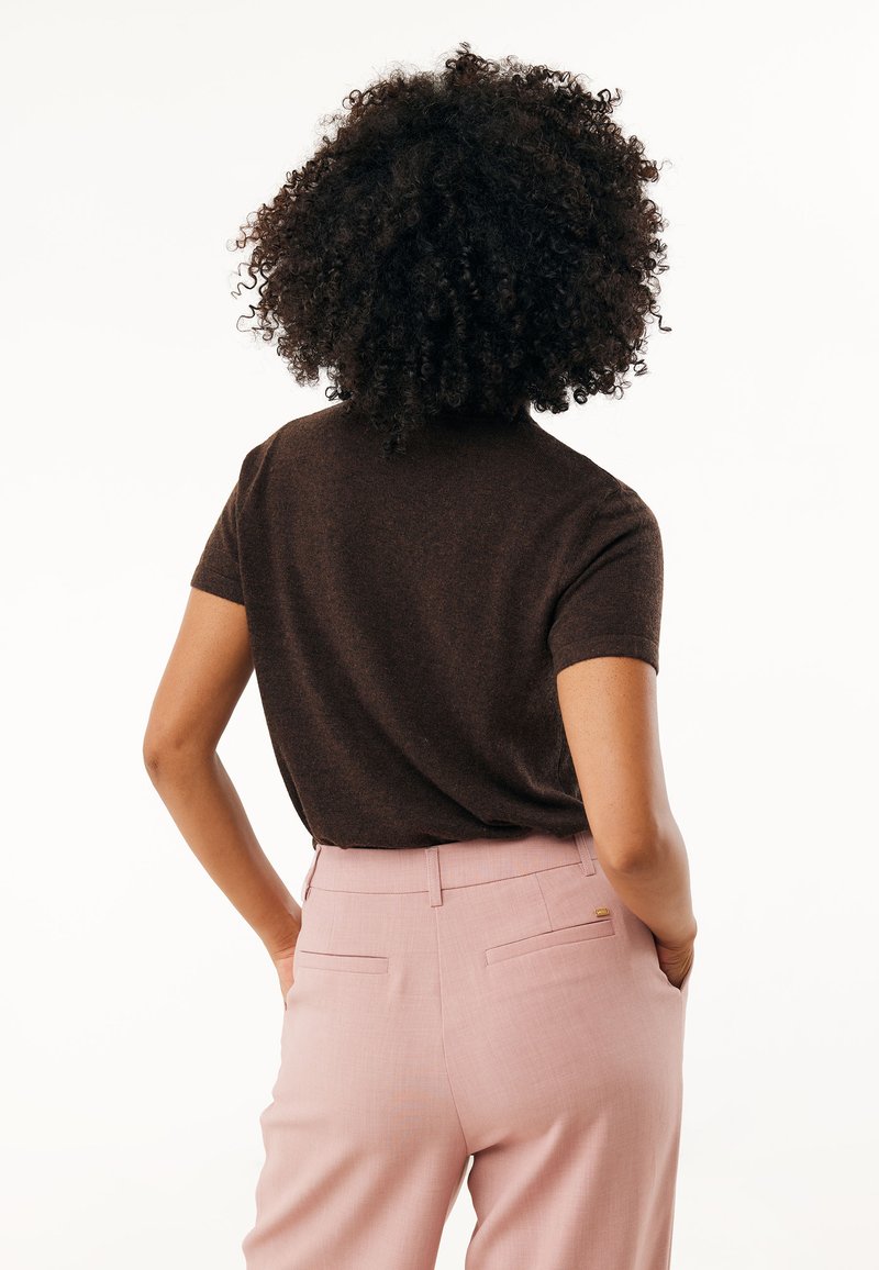 Brązowa bluzka z krótkim rękawem w połączeniu z jasnoróżowymi spodniami o dopasowanym kroju. Materiał ma gładką teksturę, z subtelnymi detalami wzoru z tyłu.