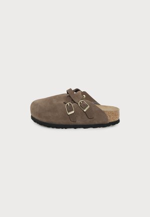 Sabot en daim marron à enfiler avec deux sangles réglables à boucle, semelle intérieure en liège et semelle extérieure en caoutchouc noir, présenté de profil sur fond blanc.