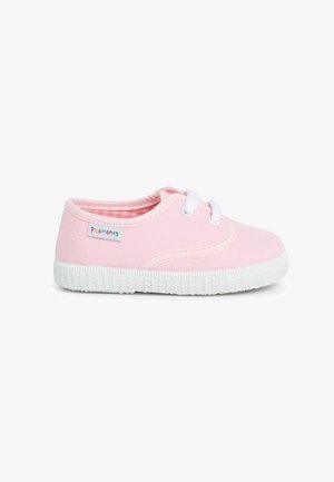Roze canvas sneaker met witte rubberen zool, vetersluiting, gestikte details en een klein multikleurig merklabel aan de zijkant.