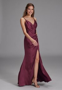 Bourgogne satin kjole med spaghetti stropper, en snoet bodice og en høj slids til låret, parret med gyldne hælesandaler. Glat tekstur.